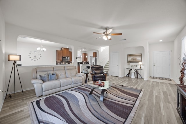 living room featuring ceiling fan with notable chandelier and light hardwood / wood-style flooring