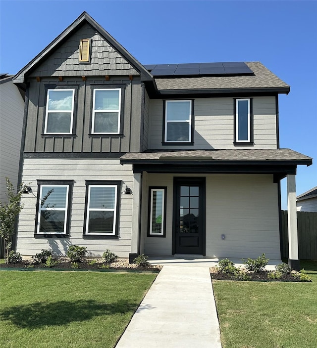 view of front of home with a front lawn and solar panels