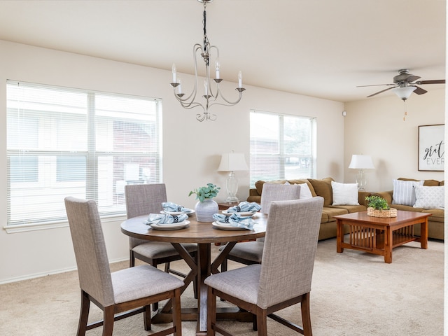 dining area featuring ceiling fan with notable chandelier and light carpet