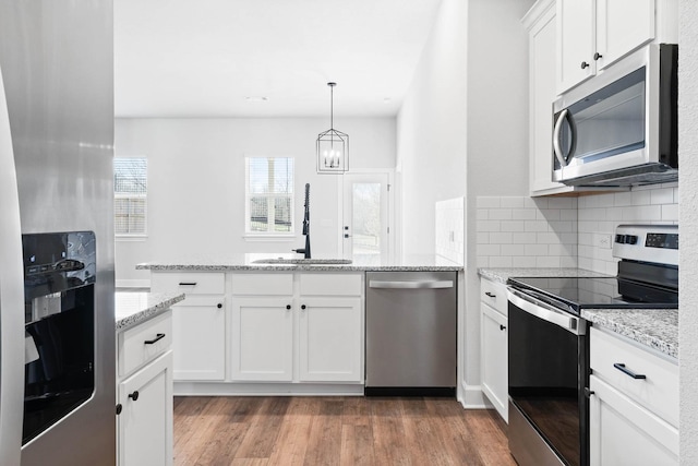 kitchen with sink, hardwood / wood-style flooring, pendant lighting, stainless steel appliances, and white cabinets