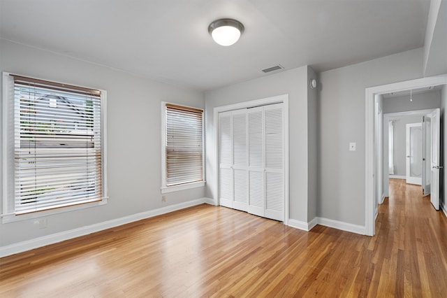 unfurnished bedroom with a closet and light wood-type flooring