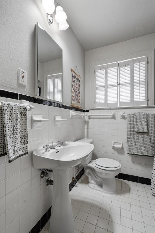 bathroom featuring toilet, tile walls, and tile patterned flooring