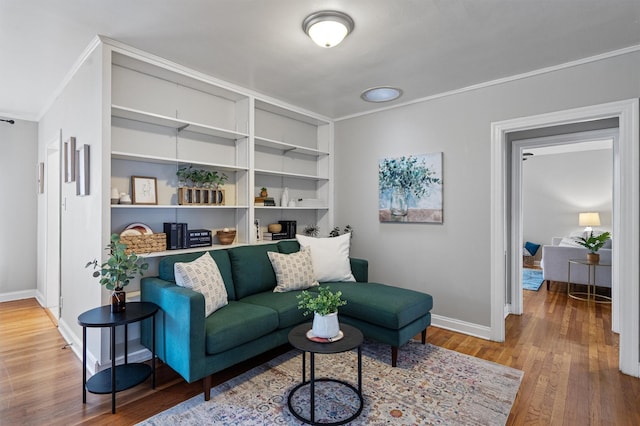 living room featuring wood-type flooring, built in features, and crown molding