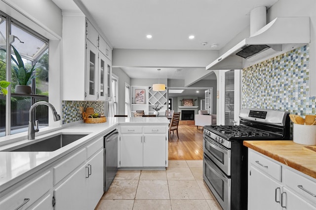 kitchen featuring white cabinets, wall chimney range hood, appliances with stainless steel finishes, and sink