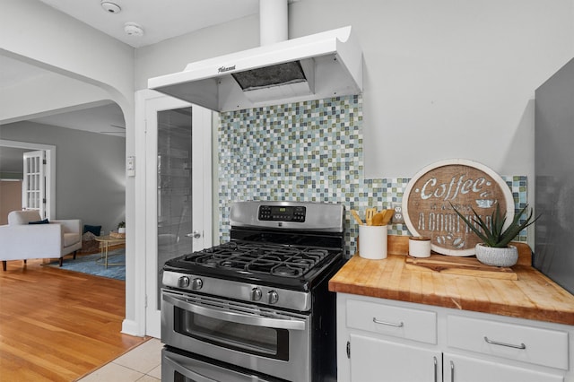 kitchen featuring extractor fan, tasteful backsplash, white cabinetry, stainless steel range with gas cooktop, and butcher block countertops