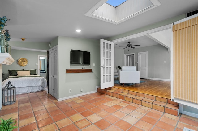 unfurnished bedroom featuring a skylight, light tile patterned floors, ceiling fan, and french doors