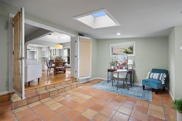 living area with vaulted ceiling with skylight and tile patterned flooring