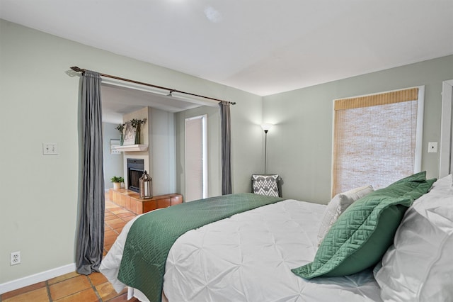 bedroom featuring a tiled fireplace and tile patterned flooring