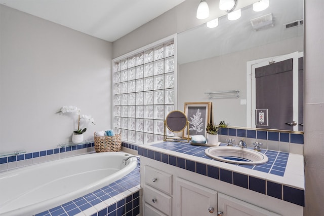 bathroom featuring vanity and tiled bath