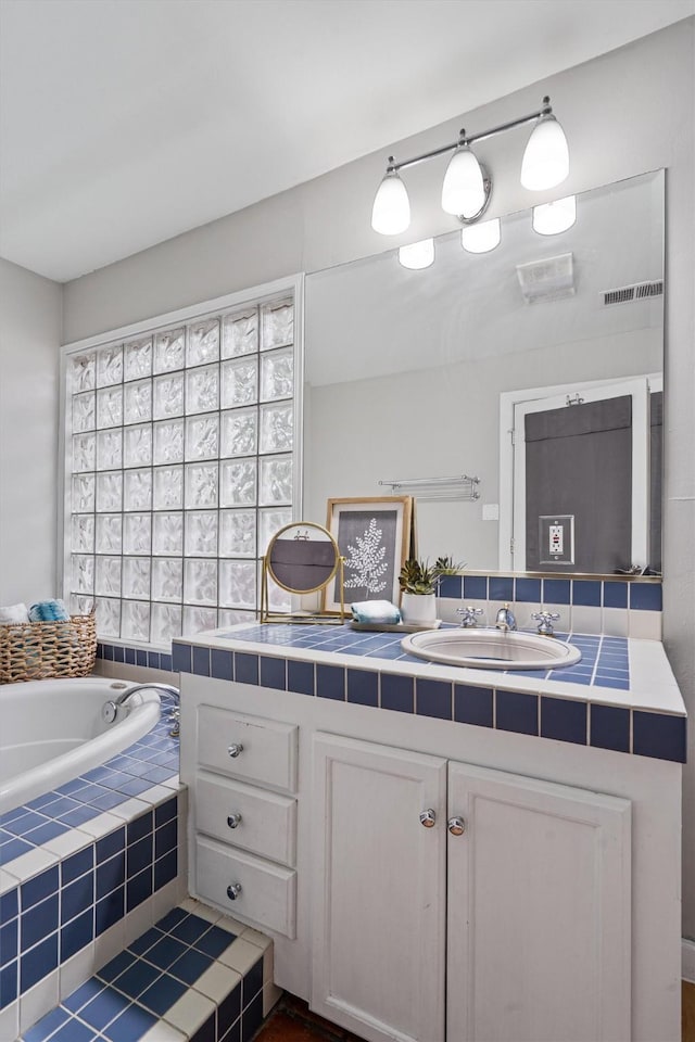 bathroom featuring vanity and tiled tub