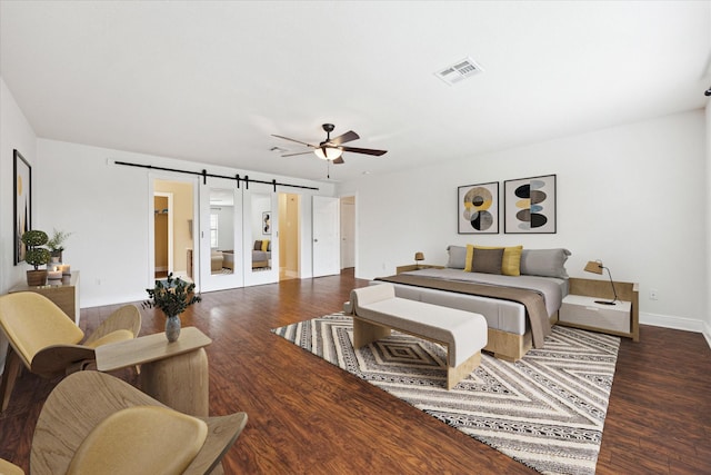 living room featuring ceiling fan, dark hardwood / wood-style floors, and a barn door