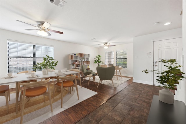 dining area featuring ceiling fan and dark tile patterned flooring