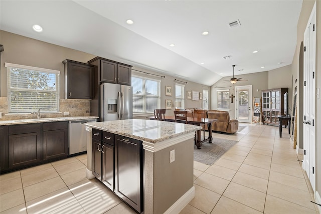 kitchen featuring dark brown cabinetry, appliances with stainless steel finishes, a center island, sink, and light tile patterned flooring