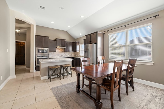 dining area with lofted ceiling and light tile patterned flooring