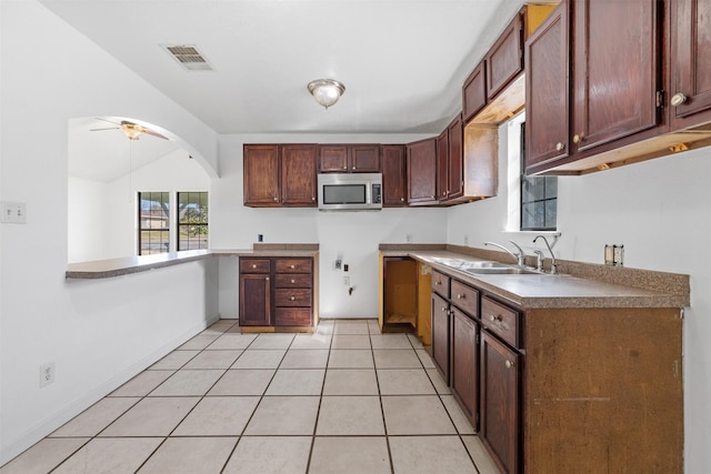 kitchen with vaulted ceiling, light tile patterned floors, sink, kitchen peninsula, and ceiling fan