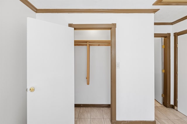 unfurnished bedroom featuring a closet, light tile patterned floors, and ornamental molding