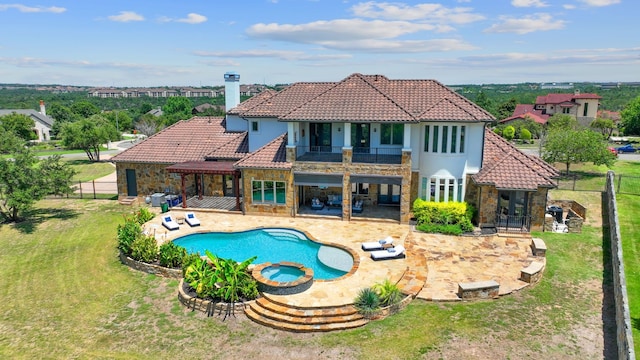 back of property featuring a balcony, a patio area, a lawn, and a pool with hot tub