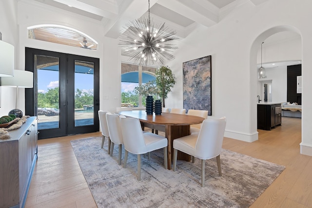 dining space with light hardwood / wood-style flooring, french doors, a chandelier, and beam ceiling