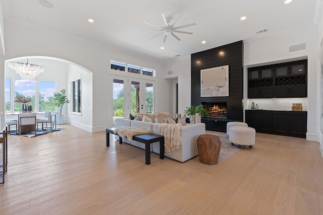 living room with a fireplace, light wood-type flooring, crown molding, and a healthy amount of sunlight