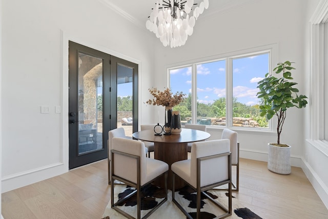 dining space featuring crown molding, light wood-type flooring, a chandelier, and french doors