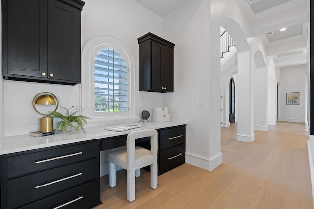 office with built in study area, ornamental molding, light wood finished floors, and baseboards