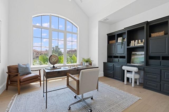 office featuring baseboards, high vaulted ceiling, light wood-style flooring, and visible vents