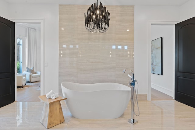 bathroom featuring a notable chandelier, a bathtub, and tile walls