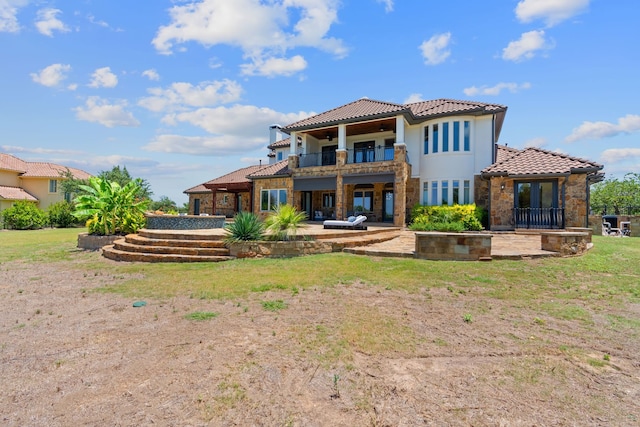 rear view of house featuring a balcony, a yard, and a patio area