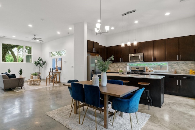 kitchen with pendant lighting, appliances with stainless steel finishes, a center island, a kitchen breakfast bar, and dark brown cabinets