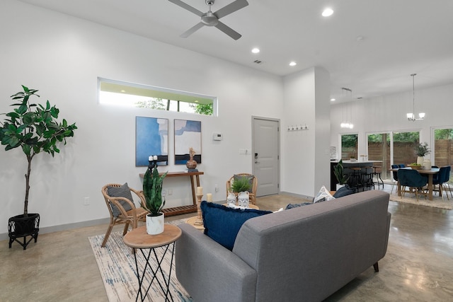 living room featuring a healthy amount of sunlight, ceiling fan with notable chandelier, and a towering ceiling