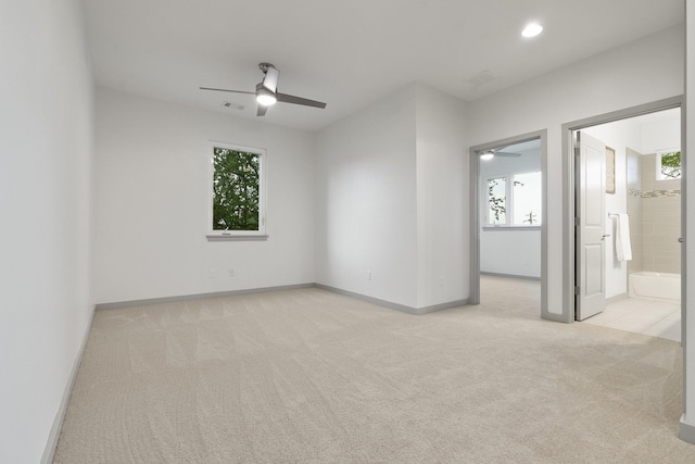 carpeted empty room with ceiling fan and a wealth of natural light