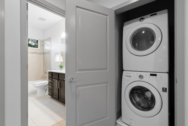 laundry area with stacked washer / dryer and light tile patterned flooring