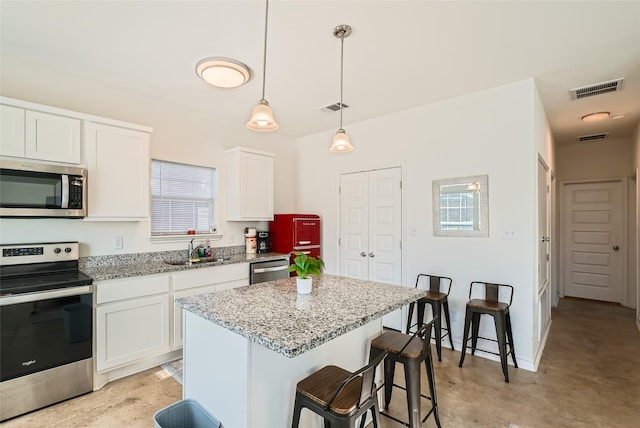 kitchen with a kitchen island, white cabinetry, a kitchen bar, and appliances with stainless steel finishes