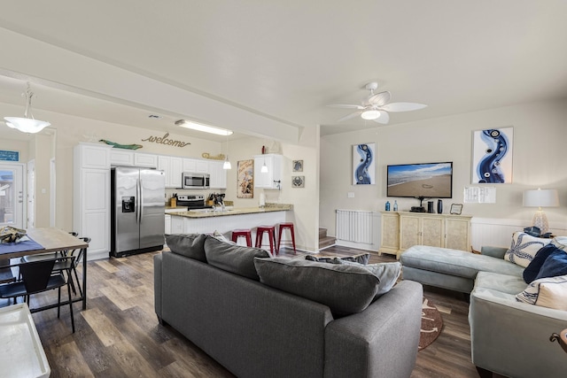 living room with ceiling fan and dark wood-type flooring