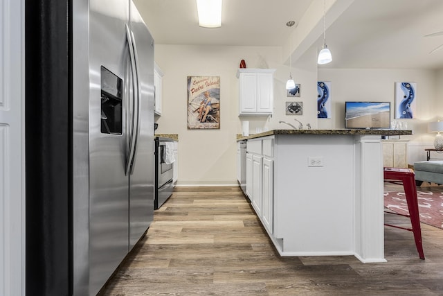 kitchen with white cabinets, appliances with stainless steel finishes, decorative light fixtures, kitchen peninsula, and light hardwood / wood-style flooring