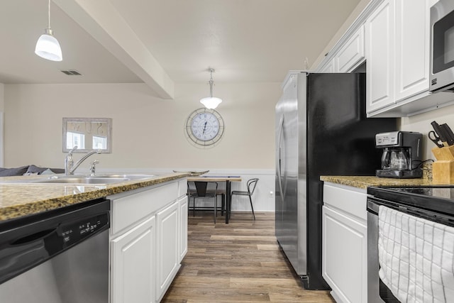 kitchen with hanging light fixtures, appliances with stainless steel finishes, sink, hardwood / wood-style flooring, and white cabinetry