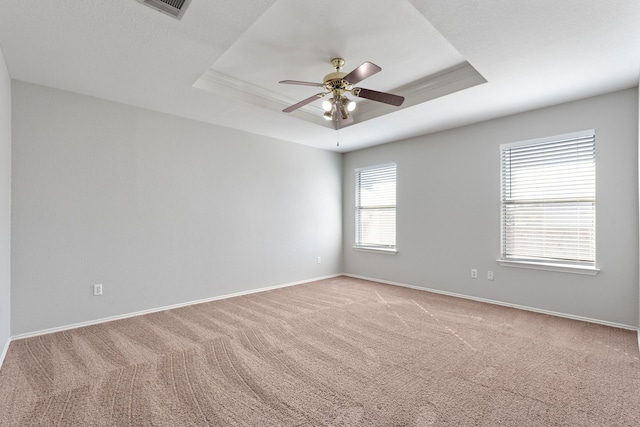 empty room featuring carpet, ceiling fan, and a tray ceiling