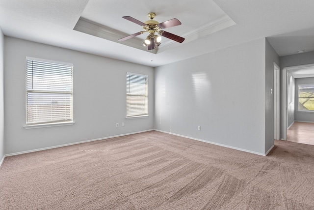 carpeted spare room with a tray ceiling and ceiling fan