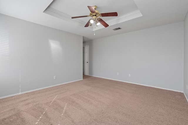 empty room with ornamental molding, carpet flooring, ceiling fan, and a tray ceiling