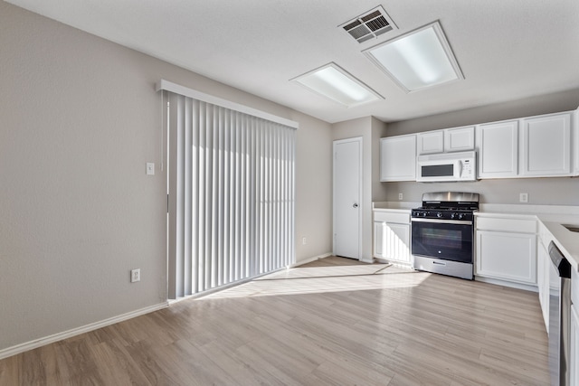 kitchen with stainless steel appliances, white cabinetry, and light hardwood / wood-style floors