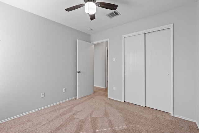 unfurnished bedroom featuring light colored carpet, a closet, and ceiling fan