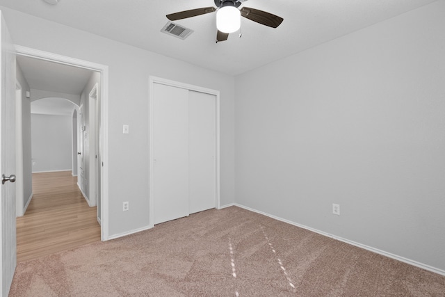 unfurnished bedroom featuring light colored carpet, a closet, and ceiling fan