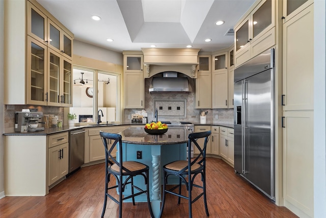 kitchen with appliances with stainless steel finishes, a kitchen island, sink, dark hardwood / wood-style floors, and a breakfast bar area