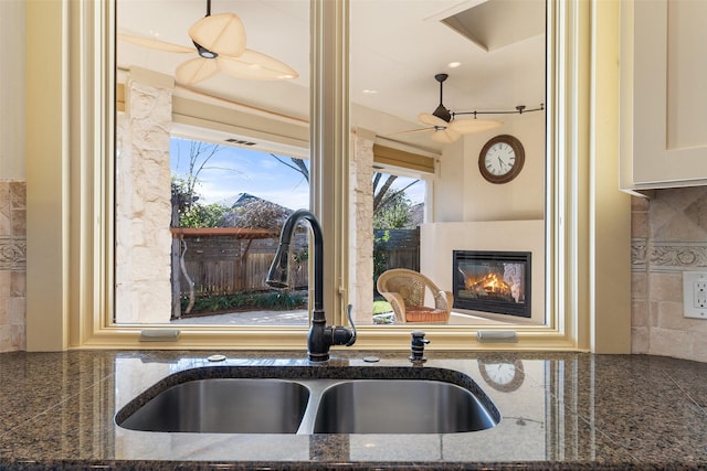 kitchen featuring sink, backsplash, dark stone counters, and cream cabinets