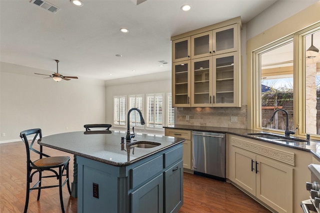 kitchen featuring sink, stainless steel dishwasher, decorative backsplash, and an island with sink