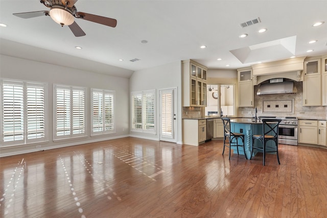 kitchen with a breakfast bar, appliances with stainless steel finishes, a kitchen island with sink, and cream cabinetry