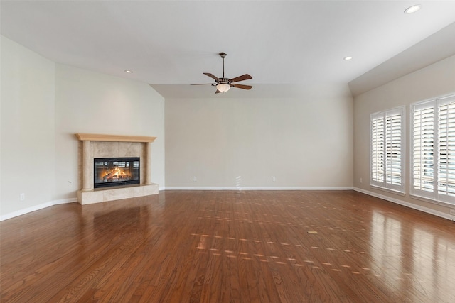 unfurnished living room featuring dark hardwood / wood-style floors, vaulted ceiling, ceiling fan, and a premium fireplace