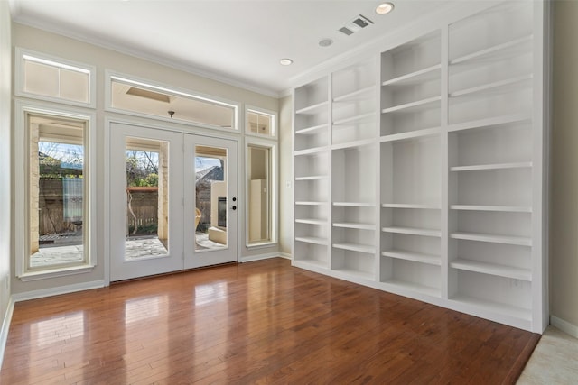 unfurnished room featuring french doors, built in shelves, ornamental molding, and hardwood / wood-style floors