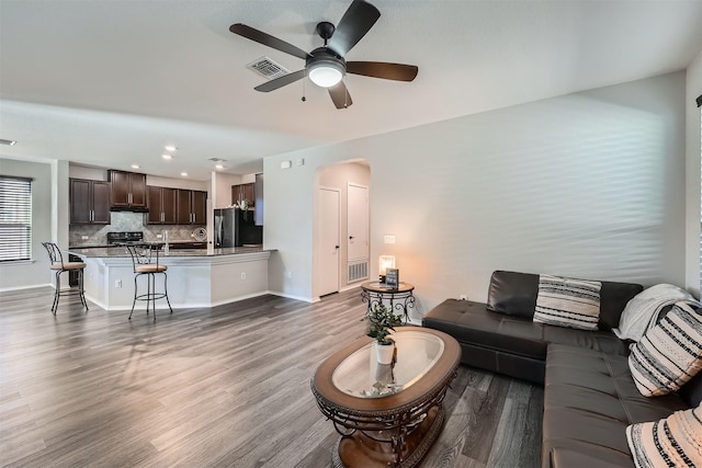 living room with ceiling fan and dark wood-type flooring