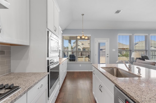 kitchen with white cabinets, appliances with stainless steel finishes, dark hardwood / wood-style flooring, sink, and light stone counters